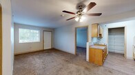 This single-floor unit offers a well-organized layout comprising three bedrooms, one full bathroom, and a kitchen. The open living area is finished with wall-to-wall carpeting and features a ceiling fan with integrated lighting. A window along the exterior wall allows natural light to fill the space, while a nearby door provides direct exterior access. The kitchen is positioned adjacent to the living area and is equipped with warm-toned wood cabinetry, laminate countertops, a stainless steel sink, and a dishwasher, offering practical functionality in a compact footprint.

The spacious primary bedroom is the largest of the three rooms, featuring carpet flooring, a window with outdoor views, a ceiling fan, and direct access to the full bathroom. The bathroom is finished with wood-look vinyl flooring and includes accessibility-friendly grab bars throughout. The two additional bedrooms are each carpeted and naturally lit by windows overlooking the exterior.

All bedrooms are equipped with sliding-door closets featuring built-in shelving and hanging rods, providing ample storage. The neutral color palette and clean finishes throughout create a simple, functional ambiance well-suited for everyday living.