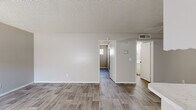 Located at 549 Sierra Vista Dr in Las Vegas, NV, this single-story, two-bedroom, one-bathroom residence offers a clean and functional layout across a compact, efficient footprint. Wood-look plank flooring runs consistently throughout the home, lending a cohesive and modern feel to every room.

The living room greets you at the entry, featuring a large window with vertical blinds that allow natural light to filter in, a textured ceiling, and neutral-toned walls that create a bright, open atmosphere. The galley-style kitchen is well-appointed with white cabinetry, a tile backsplash, light countertops, a gas range, and a full-size refrigerator. A peninsula counter with additional workspace adds functionality, while a ceiling fan overhead keeps the area comfortable.

The primary bedroom is generously sized and includes a sliding-door closet with dual hanging rods, providing ample storage. The second bedroom features its own window for natural light and shares the same wood-look flooring. The full bathroom offers a tub and shower combination accented by a distinctive colorful tile window feature, a vanity with a marble-look countertop, and wood-tone flooring. Textured ceilings are present throughout, adding a classic touch to this straightforward and well-maintained Las Vegas residence.