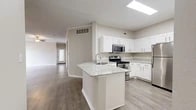 Located at 2825 N Highway 360 in Grand Prairie, TX, this single-story, 2-bedroom, 2-bathroom home offers a thoughtfully designed layout with modern finishes throughout. The open-concept kitchen and living area serves as the heart of the home, featuring a granite-topped center island with a built-in sink, crisp white shaker cabinetry, and a full suite of stainless steel appliances including a range, microwave, and refrigerator. Wood-look plank flooring extends through the kitchen and living areas, while crown molding and a ceiling fan lend character to the spacious living room, which also includes a sliding door for additional light. Both bedrooms are carpeted and equipped with ceiling fans, offering a comfortable retreat. The primary bedroom is generously sized and connects to a well-appointed full bathroom featuring a granite-topped double vanity with white cabinetry, wood-look flooring, and a tub-shower combo with white tile surround. A dedicated walk-in closet with wire shelving provides ample storage. The second bathroom also includes a tub-shower combo with white tile. Hallways connect the spaces efficiently, completing this clean and functional single-floor layout.