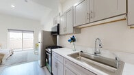 Located at 983 Dewey Ave in Los Angeles, CA, this thoughtfully designed one-bedroom, one-bathroom unit offers a clean, modern aesthetic throughout its efficiently organized single floor. The open layout connects the bedroom and kitchen areas seamlessly, creating a bright and airy atmosphere enhanced by light-toned flooring and neutral white walls throughout.

The spacious bedroom is the heart of the unit, featuring large sliding glass doors that open onto a private balcony with open views of the surrounding neighborhood. Natural light fills the room generously, contributing to a warm and welcoming ambiance. A mirrored sliding closet provides convenient storage within the bedroom.

The kitchen is well-appointed with gray shaker-style cabinetry, white countertops, and stainless steel appliances including a gas range, refrigerator, and dishwasher. A stainless steel sink and modern faucet complete the functional and stylish kitchen space.

The bathroom showcases standout finishes, including a striking marble-tiled walk-in shower with glass enclosure, a bold navy blue vanity with brushed gold hardware, and light wood-look flooring that ties the room together elegantly.

Light wood-look flooring runs through the kitchen and bathroom areas, while plush carpeting adds comfort to the bedroom. The unit's clean, contemporary design and quality finishes make it a polished and practical living space in the heart of Los Angeles.