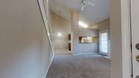 Located in Dallas, TX, this two-story, 2-bedroom, 4-bathroom home offers a thoughtfully designed layout spread across two floors. The main level impresses with a dramatic vaulted ceiling that soars above the open-concept living and dining area, which is anchored by a classic wood-mantled fireplace and bathed in natural light from multiple windows adorned with blinds. A ceiling fan adds comfort overhead, while plush carpeting flows throughout the living spaces. The kitchen opens to the living area via a pass-through counter, featuring dark wood cabinetry, white appliances including an electric range and refrigerator, and durable hardwood-style flooring. A dedicated in-unit laundry area with a Whirlpool washer provides added convenience. The primary bedroom is generously sized, complete with a ceiling fan, carpet flooring, and direct access to a bathroom that features granite countertops, wood cabinetry, a mirrored sliding closet, and a shower-tub combo with clean white tile surround. The second bedroom is equally comfortable, also carpeted and well-lit with natural light. Three closets throughout the home provide ample storage, and a central hallway and staircase connect both levels seamlessly.