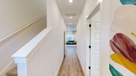 Located in Rogers, Arkansas, this two-story home features a clean, modern aesthetic with white walls, light wood-style flooring, and an abundance of natural light throughout. The main floor hosts the open-concept kitchen and living area, where the kitchen stands out with white shaker cabinetry, granite countertops, a central island with a built-in sink and pendant lighting, and stainless steel appliances. The adjacent living room is bright and welcoming, featuring large windows with sheer curtains, elevated transom windows, and a ceiling fan that enhances the airy feel. A hallway with recessed lighting connects the main living spaces to a staircase leading to the upper floor. The three bedrooms are carpeted and feature ceiling fans, natural light from well-positioned windows, and ample closet space, including a walk-in closet with built-in shelving and hanging rods. The five bathrooms are finished with granite-topped vanities, white cabinetry, matte black hardware, and tub-shower combinations with built-in shelving. The upper floor offers a more intimate layout, housing additional bedrooms and bathrooms. Throughout the home, consistent finishes and a neutral palette create a cohesive, comfortable environment suitable for everyday living.