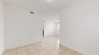 Located at 2421 W 78th St in Hialeah, FL, this single-floor apartment offers a practical and well-organized layout across three bedrooms and two full bathrooms. Light beige ceramic tile flooring runs consistently throughout the entire unit, creating a cohesive, easy-to-maintain interior. The living room is bright and open, with a window dressed in sheer curtains that allows natural light to fill the space near the entry door. The kitchen is well-appointed with rich cherry wood cabinetry, granite-style countertops, a stainless steel double sink, and a white electric range with overhead ventilation. A window above the counter brings in additional natural light and outdoor views. The three bedrooms are clean and simply designed with white walls and tile flooring; one bedroom features a windowed wall with blinds providing outdoor views, while another includes a built-in closet with wire shelving. Both bathrooms are consistently finished with beige ceramic tile surrounds in the tub-shower combinations, cherry wood vanities, granite-style countertops, and tile flooring. A hallway connects the rooms efficiently, and a dedicated closet adds storage convenience. The overall ambiance is clean, neutral, and move-in ready.