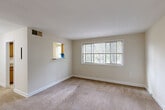 Located at 8810 Lanier Dr in Silver Spring, Maryland, this two-bedroom, one-bathroom single-floor residence offers a well-organized and functional layout. The combined living and dining area is generously sized, featuring neutral-toned carpet, soft beige walls, and a distinctive green entry door that adds a pop of character. Large windows allow natural light to fill the space while offering views of surrounding greenery. A chandelier in the dining area provides an elegant accent overhead.

The galley-style kitchen is efficiently arranged with warm wood cabinetry, ample counter space, tile flooring, and a full suite of white appliances including a refrigerator, electric range, built-in microwave, and dishwasher. A window above the counter brings in additional natural light.

The spacious primary bedroom is generously proportioned, with carpet flooring, a large multi-pane window with outdoor views, and a pass-through window detail on one wall. The second bedroom is similarly finished with carpet and a window. Both bedrooms benefit from access to the four closets distributed throughout the unit.

The bathroom is clean and functional, featuring tile flooring, a vanity with wood cabinetry, a wall mirror, and a multi-bulb light fixture. A hallway connects all rooms, providing a logical and efficient flow throughout the residence.