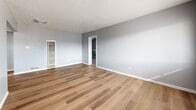 Located at 1015 Cardenas Dr SE in Albuquerque, New Mexico, this single-story 2-bedroom, 1-bathroom home offers a functional and comfortable layout. The living room greets you with warm wood-look vinyl plank flooring, soft gray walls, a textured ceiling, and a front-facing window that fills the space with natural light. A wall heater provides efficient climate control, and an open doorway connects seamlessly to the rest of the home.

The combined kitchen and dining area is efficiently designed with white cabinetry accented by wood trim, white countertops, and matching white appliances including a refrigerator and range. Light wood-look flooring continues throughout, and a window at the far end brings in additional natural light. A ceiling fan overhead adds to the room's practicality.

Both bedrooms feature plush neutral carpet, ceiling fans, textured ceilings, and natural light from windows. The spacious primary bedroom includes a built-in desk nook flanked by closet space, offering convenient storage and workspace. The second bedroom also includes a wall-mounted AC unit and a closet. Four closets total are distributed throughout the home.

The bathroom is clean and bright, featuring a wood-toned vanity with a white countertop, a large mirror, and a full tub and shower surround with a window above for ventilation.