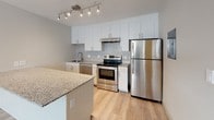 Located at 4701 N Academy Blvd in Colorado Springs, CO, this single-floor residence offers a thoughtfully designed layout with modern finishes and functional living spaces. The kitchen serves as a standout feature, showcasing white shaker-style cabinetry, granite countertops, and a full suite of stainless steel appliances including a refrigerator, electric range, and dishwasher. A geometric-patterned tile backsplash adds visual interest, while track lighting overhead ensures a bright, well-lit workspace. Light wood-style flooring flows throughout the kitchen and main living areas, contributing to an open, airy feel. The bedrooms are carpeted for comfort and each feature ceiling fans with integrated lighting, natural light from windows with blinds, and baseboard heating. One bedroom includes access to a walk-in closet and an adjoining bathroom, providing added privacy and convenience. The bathroom is clean and functional, featuring a tiled tub-and-shower combination with brushed nickel fixtures and a granite vanity surface. Textured ceilings are present throughout the sleeping areas, adding a classic residential touch. The overall layout, as seen in the dollhouse view, is efficiently organized with clear separation between the living, kitchen, and bedroom spaces.