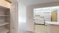 This single-floor residence offers a clean, straightforward layout designed for comfortable everyday living. The kitchen is efficiently arranged with white cabinetry above and below the counter, a double-basin sink, a gas range, and a full-size refrigerator. A distinctive dropped grid ceiling with integrated lighting panels brightens the space, while tile flooring adds a practical touch underfoot.

From the entry hallway, the transition into the carpeted living area is seamless. The living room is generously sized, featuring soft neutral carpet and a sliding glass door that opens to a private balcony, allowing natural light to fill the room and providing pleasant outdoor views. A ceiling fan is present in an adjacent room, adding to the overall comfort of the space.

The bedrooms are well-proportioned with plush carpeting, white walls, and windows that bring in natural light while offering views of the surrounding greenery. Each room provides a calm, neutral canvas adaptable to various uses.

The bathroom is equipped with white tile flooring, a full bathtub with tiled surround, a toilet, and a vanity with counter space, maintaining the clean and functional aesthetic found throughout the rest of the space.