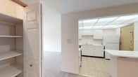 This single-floor residence offers a clean, straightforward layout designed for comfortable everyday living. The kitchen is efficiently arranged with white cabinetry above and below the counter, a double-basin sink, a gas range, and a full-size refrigerator. A distinctive dropped grid ceiling with integrated lighting panels brightens the space, while tile flooring adds a practical touch underfoot.

From the entry hallway, the transition into the carpeted living area is seamless. The living room is generously sized, featuring soft neutral carpet and a sliding glass door that opens to a private balcony, allowing natural light to fill the room and providing pleasant outdoor views. A ceiling fan is present in an adjacent room, adding to the overall comfort of the space.

The bedrooms are well-proportioned with plush carpeting, white walls, and windows that bring in natural light while offering views of the surrounding greenery. Each room provides a calm, neutral canvas adaptable to various uses.

The bathroom is equipped with white tile flooring, a full bathtub with tiled surround, a toilet, and a vanity with counter space, maintaining the clean and functional aesthetic found throughout the rest of the space.