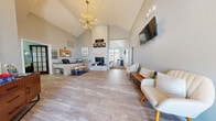 Located at 20 Brickyard Dr in Bloomington, Illinois, this single-floor community clubhouse serves as a central hub for residents. The space is defined by soaring vaulted ceilings and an open, airy layout that creates an impressive sense of scale throughout.

The main lobby and reception area greet visitors with warm wood-look tile flooring, a dramatic floor-to-ceiling stone fireplace, and a wall-mounted TV. A sputnik chandelier adds a modern design touch, while large windows and transom glass draw in abundant natural light. A staffed leasing desk is conveniently positioned near the entrance.

Adjacent to the lobby, a well-appointed lounge and community room features plush carpeting, wainscoting, and comfortable seating arrangements alongside a central dining table — ideal for gatherings or casual meetings. French doors with glass panels lend an elegant transition between spaces.

The on-site kitchen includes light wood cabinetry, white appliances, ample counter space, and tile flooring, providing practical amenities for community events.

The fitness center is a standout feature, boasting high ceilings, large windows for natural light, rubber flooring, full-wall mirrors, and a comprehensive selection of equipment including cardio machines, free weights, medicine balls, and a cable machine — catering to a wide range of workout preferences.