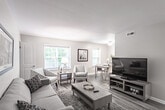 Located at 201 Tam-O-Shanter Blvd in Williamsburg, Virginia, this single-floor residence offers a well-organized and cohesive layout designed for comfortable everyday living. Wood-look flooring flows throughout the home, providing a warm, unified aesthetic across all rooms.

The living room is a welcoming, open space featuring neutral walls and large windows dressed with blinds that allow natural light to fill the room. The dining area, adjacent to the living space, includes a window overlooking lush greenery, creating a bright setting for meals.

The galley-style kitchen is efficiently designed with white shaker cabinetry, granite-style countertops, a stainless steel sink, and a full suite of stainless steel appliances including a refrigerator, range, and dishwasher. Light-toned flooring complements the clean, modern finish.

The home includes multiple bedrooms, each finished with the same wood-look flooring and neutral walls. The primary bedroom features a walk-in closet, while additional bedrooms offer their own closet storage and windows that frame natural outdoor views. The bathroom is cleanly appointed with a white vanity, tub-shower combination, and coordinating fixtures, maintaining the home's consistent, understated style throughout.