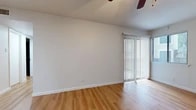 This single-floor residence offers a clean, functional layout with warm hardwood-style flooring running consistently throughout. The living area is generously sized, bathed in natural light streaming through a large sliding glass door fitted with vertical blinds, which provides outdoor access and an open, airy feel. A ceiling fan overhead adds to the room's comfort. An additional window further brightens the space, offering views of the surrounding exterior.

The galley-style kitchen is efficiently arranged, featuring dark cabinetry, laminate countertops, a stainless steel sink, and white appliances including a dishwasher, range, and full-size refrigerator. A window above the sink allows for natural light to fill the workspace.

The bedrooms are well-proportioned, each equipped with ceiling fans and windows that invite natural light. One bedroom features a spacious walk-in closet with built-in shelving, providing ample storage. An additional walk-in closet with a shelving system is also present elsewhere in the unit.

The bathroom is clean and straightforward, outfitted with a full bathtub and tiled surround in a bright white finish. Throughout the space, neutral wall tones and consistent flooring create a cohesive and inviting atmosphere that is move-in ready.
