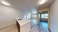 Located at 9365–9499 N 99 Frontage Rd in Stockton, California, this modern single-story residence offers a clean, contemporary design throughout. The open-concept layout seamlessly connects the kitchen and living area, creating a bright and functional common space. The kitchen features a peninsula with a white quartz-style countertop and a stainless steel undermount sink with a professional-style pull-down faucet. Dark espresso cabinetry with brushed metal hardware contrasts beautifully against the light countertops, while stainless steel appliances — including a gas range, over-the-range microwave, and refrigerator — complete the space. Light hardwood-style flooring flows throughout, enhancing the airy feel of the interior. The spacious living area is illuminated by multiple windows that invite natural light and is equipped with a ceiling fan. The bedroom offers ample space, a ceiling fan, a dedicated closet, and a window with exterior views. An en-suite bathroom includes a vanity with a warm-toned countertop, white cabinetry, a large mirror, and a tub/shower combination. A second full bathroom mirrors the same clean, neutral aesthetic with a white tiled tub surround and brushed nickel fixtures throughout.