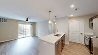 This 2-bedroom, 2-bathroom residence at 3506 Bluff Rd in Indianapolis offers a well-designed, single-floor layout with modern finishes throughout. The open-concept kitchen and living area serves as the heart of the home, anchored by a central island featuring a white quartz countertop and undermount sink, illuminated by stylish pendant lighting. The kitchen is equipped with stainless steel appliances, including a refrigerator, range, and microwave, complemented by rich dark-wood cabinetry and light wood-style flooring. A dedicated walk-in pantry provides generous storage. The living area extends naturally toward sliding glass doors that open onto a private balcony, filling the space with natural light. Both bedrooms are carpeted and include ceiling fans; the primary bedroom offers a comfortable footprint with a bright window and closet access. The two bathrooms are finished with dark wood vanities, white countertops, and light wood-style flooring — one featuring a tub-shower combination. Two dedicated closets add practical storage. The neutral color palette and clean architectural lines give the entire space a bright, contemporary feel.