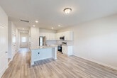 This two-story home in Fort Oglethorpe, Georgia offers a thoughtfully designed layout spread across two floors. The main level provides a generous living area anchored by an open-concept kitchen and living room. The kitchen is well-equipped with white shaker-style cabinetry, a subway tile backsplash, stainless steel appliances including a range, built-in microwave, refrigerator, and dishwasher, and a central island featuring a granite countertop and undermount sink — ideal for both cooking and casual dining. Light wood-tone luxury vinyl plank flooring runs throughout, adding warmth and continuity to the space. The main floor also includes the primary bedroom, which offers a private en-suite bathroom and a dedicated closet, along with access to the attached garage and a laundry area. Upstairs, the second floor hosts a loft space, two additional bedrooms, and two full bathrooms. Each bathroom features white vanities with granite-style countertops and tub/shower combinations. Five closets throughout the home provide ample storage. The overall aesthetic is clean and modern, with neutral tones, recessed lighting, and bright, windowed rooms creating a fresh and inviting atmosphere throughout.