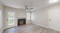 Located at 1212 Chase Heritage Cir in Sterling, Virginia, this single-floor home offers a thoughtfully designed layout with contemporary finishes throughout. The living area serves as the heart of the home, showcasing durable wood-look flooring, a sleek electric fireplace with a dark surround and white mantel, and a ceiling fan overhead. Natural light filters in through multiple windows dressed with white blinds, creating a bright and welcoming ambiance.

The kitchen is outfitted with crisp white shaker-style cabinetry, light stone countertops, and a full suite of stainless steel appliances, including a refrigerator, electric range, and over-the-range microwave. A peninsula with a sink adds functional prep and dining space.

The bedrooms feature plush wall-to-wall carpeting and ceiling fans, with one bedroom benefiting from a sliding glass door that opens to an outdoor view, bringing in generous natural light. Neutral-toned walls throughout the home lend a clean, cohesive aesthetic.

The bathroom is finished in a clean, all-white palette with subway tile surrounding a soaking tub and shower combination, wood-look flooring, and recessed lighting. Additional utility space provides laundry connections and ample room for storage, completing this move-in-ready home.