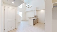 Located at 8521 Sepulveda Blvd in Los Angeles, CA, this two-story residence offers a thoughtfully designed layout spread across two well-proportioned floors. The main level greets you with a dramatic double-height ceiling in the open living area, bathed in natural light from large windows. Light wood-tone flooring flows throughout, lending a clean, contemporary aesthetic to the entire space. A stylish chandelier anchors the living area, while a peninsula kitchen features white cabinetry, quartz countertops, a tile backsplash, and a full suite of stainless steel appliances including a side-by-side refrigerator, electric range, and over-the-range microwave. A dedicated in-unit laundry closet with a stacked washer and dryer adds everyday convenience. A staircase with a modern white railing leads to the upper level, where plush carpeting transitions from the lower floor's hardwood. The upper level features a bright, generously sized bedroom with a natural light-filled window and a neutral color palette. The full bathroom is well-appointed with a tiled shower/tub combo, built-in open shelving, and a vanity with ample counter space. Clean lines, recessed lighting, and a crisp all-white palette throughout create a fresh and inviting atmosphere ideal for comfortable urban living.