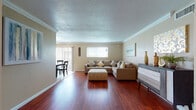 This single-story, 3-bedroom, 2-bathroom home offers a thoughtfully designed layout that balances comfort and functionality. Crown molding is a consistent architectural detail throughout, adding a refined finish to each room.

The living room serves as the central gathering space, featuring rich hardwood flooring, a textured ceiling, and windows that allow natural light to fill the room. Adjacent to the living area, the dining room is finished with tile flooring, a ceiling fan with lighting, and a sliding glass door that opens to an outdoor patio, enhancing the sense of openness.

The galley-style kitchen is efficiently arranged with ample white cabinetry, dark granite-style countertops, a double sink, and tile flooring, with a secondary door providing convenient access.

The primary bedroom features hardwood floors, crown molding, a ceiling fan, and a window with natural light. A second bedroom, also with hardwood floors and crown molding, offers versatile sleeping arrangements. The third bedroom continues the warm hardwood flooring and includes a ceiling fan.

The two bathrooms are finished with tile flooring and include a tub-shower combination. The home maintains a cohesive, neutral color palette throughout, creating a warm and welcoming ambiance.