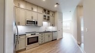 This efficiently designed 620 square foot apartment offers a blend of comfort and functionality. The single-floor layout includes one bedroom, measuring 120 square feet, and two bathrooms, providing ample personal space. The heart of the home is an open-concept kitchen and living room area, perfect for entertaining or relaxing.

Natural light floods the space through large windows, creating a bright and airy atmosphere. The neutral color palette, featuring light gray walls, adds to the sense of spaciousness. Durable wood-look flooring extends throughout, offering both aesthetic appeal and easy maintenance.

A notable feature is the glass-paned door, likely leading to a small balcony or patio, further extending the living space. The room's clean lines and minimalist design contribute to a modern, uncluttered feel. Recessed lighting and a central ceiling fixture provide adaptable illumination options.

Storage needs are addressed with a dedicated closet space, essential in compact urban living. The overall design prioritizes functionality without sacrificing style, making it an ideal choice for those seeking an efficient yet comfortable living environment in a city setting.