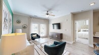 Located at 195 N Creek Dr in Summerville, SC, this single-floor residence offers a thoughtfully designed open-concept layout that seamlessly connects the kitchen, dining, and living areas. The kitchen is a standout feature, boasting rich dark-brown cabinetry, stainless steel appliances, a tiled backsplash, and a large center island with a built-in sink and bar seating — ideal for both cooking and casual dining. Light wood-look flooring runs throughout the main living areas, complementing the neutral color palette and creating a bright, cohesive aesthetic. The living room is spacious and inviting, highlighted by a ceiling fan, large French doors that allow natural light to pour in, and direct access to an outdoor area. Two well-sized bedrooms feature plush carpeting and ample natural light. The primary bedroom includes an en-suite bathroom with a dual-sink vanity, dark cabinetry, a large framed mirror, and wood-look tile flooring. A second full bathroom offers a single-sink vanity with matching cabinetry and finishes. A dedicated in-unit laundry space houses a full-size washer and dryer with built-in wire shelving for added storage. The overall ambiance is modern and comfortable, making this Summerville residence a refined and functional living space.