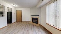 Located at 988 Yellow Brick Rd in Chaska, MN, this one-bedroom, one-bathroom unit offers a thoughtfully arranged single-floor layout that maximizes every square foot. The living room serves as the heart of the space, highlighted by a tile-surround fireplace with a sleek dark mantle and a large picture window that frames outdoor greenery, flooding the room with natural light. Light wood-look laminate flooring runs throughout the main living areas, lending a clean, modern feel, while a textured ceiling adds a classic touch. A private exterior door provides convenient outdoor access directly from the living area. The kitchen features light gray cabinetry with contemporary hardware, a mosaic tile backsplash, light stone-look countertops, and a full suite of black appliances including a range, microwave, dishwasher, and refrigerator. A half-wall with a pass-through opening connects the kitchen to the dining and living areas, with a ceiling fan overhead enhancing airflow. The spacious bedroom is carpeted for comfort, offers generous closet space with wood sliding doors, and includes a window with outdoor views. The bathroom is finished with a full tub-shower combo, a wood-toned vanity with a white countertop, and classic tile flooring.