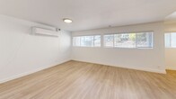 Located at 740 W 24th St in San Pedro, Los Angeles, this two-bedroom, one-bathroom residence offers a clean, modern interior across a single floor. Light wood-style flooring runs throughout the space, creating a cohesive and airy feel.

The kitchen is well-appointed with white shaker cabinetry extending to the ceiling, granite-style countertops, and a full suite of stainless steel appliances including a gas range, microwave, and dishwasher. Adjacent to the kitchen is a dining area with a window that brings in natural light.

The living room is open and bright, with white walls and light flooring that together create a neutral, versatile backdrop. The primary bedroom is generously sized and features a walk-in closet, a wall-mounted mini-split HVAC unit, and multiple windows offering views of the surrounding neighborhood. The second bedroom includes a sliding glass door with vertical blinds, allowing for natural light and outdoor access.

The bathroom is finished in a clean, all-white palette with a shaker-style vanity, white cabinetry with built-in storage above the tub, a large mirror, and a shower/tub combination. The hallway connects all rooms efficiently, contributing to a functional and straightforward layout throughout the home.