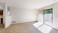 Located at 701 E Summit View Pl in Bloomington, Indiana, this one-bedroom, one-bathroom unit offers a functional and well-organized single-floor layout. Neutral-toned carpet flows throughout the main living areas, creating a cohesive and clean aesthetic. The combined kitchen and living room forms the heart of the unit, where a sliding glass door with vertical blinds fills the living area with natural light and provides access to an outdoor view. The kitchen is equipped with warm wood cabinetry, a white appliance suite including an electric range, dishwasher, and refrigerator, along with a countertop peninsula that adds convenient workspace and a casual dining option. Tile flooring anchors the kitchen area. The bedroom is a generously sized room featuring a window with blinds that allows natural light to stream in, plush carpeting, and a ceiling fan overhead, contributing to a comfortable and restful environment. The dedicated closet provides practical storage. The bathroom includes a vanity with wood cabinetry and a large mirror, tile flooring, and a bathtub with shower, all presented in a clean, light-toned palette. Throughout the unit, the design is simple and practical, offering a welcoming living environment.