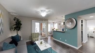 This single-floor residence offers a well-organized layout that connects key living spaces in a functional and visually cohesive design. The living room serves as the central gathering area, finished with wood-look flooring, a ceiling fan, and a teal accent wall that adds a bold pop of color against the neutral gray walls. Sliding glass doors allow natural light to fill the room and provide access to an outdoor area. The open-concept design flows directly into the kitchen and dining spaces, separated by a peninsula counter with granite-look surfaces and a teal base that echoes the living room's color palette. The kitchen is equipped with dark cabinetry, stainless steel appliances including a refrigerator, microwave, and range, complemented by a tile backsplash and pendant lighting. The adjacent dining area accommodates a full-sized table and benefits from natural light through a window. The bedrooms are comfortably sized, each featuring ceiling fans, wood-look flooring, and windows fitted with blinds. The bathroom includes a tub-shower combination, a dark-framed vanity mirror, and ample counter space. A dedicated laundry room houses a full-sized washer and dryer with overhead wire shelving for additional storage.