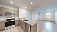 This two-floor residence offers 3 bedrooms and 3 bathrooms across a well-designed layout, with the majority of the living space situated on the upper floor. The open-concept kitchen and living area serves as the heart of the home, featuring light wood-style flooring, recessed lighting, and a large central island with granite countertops and an undermount sink. The kitchen is equipped with stainless steel appliances, including a range, microwave, dishwasher, and refrigerator, complemented by taupe cabinetry and a clean white tile backsplash. Natural light flows through multiple windows, enhancing the bright, airy ambiance throughout.

The three bedrooms are finished with plush carpeting and ceiling fans, offering a comfortable retreat. The generously sized primary bedroom includes a dedicated en-suite bathroom with a walk-in glass shower, while additional bedrooms are well-proportioned with ample natural light from large windows. Each of the three bathrooms maintains consistent finishes, including granite-topped vanities and light wood-style flooring. One bathroom features a full tub-shower combination with white tile surround.

Storage is well-addressed, with three closets including a walk-in closet outfitted with built-in shelving and hanging rods. A carpeted staircase with a handrail connects the two floors, completing this thoughtfully arranged home.
