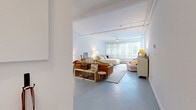 Located at 2050 Scotia St in Vancouver's vibrant Mount Pleasant neighbourhood, this open-concept studio offers a loft-inspired design that maximizes every square foot of its single-floor layout. The main living area is expansive and airy, characterized by crisp white walls, smooth concrete-style tile flooring, and industrial-style track lighting that runs across the ceiling. A ceiling fan adds both function and a casual aesthetic to the space.

The living, dining, and sleeping areas flow seamlessly together in one generous open room. A wide bank of floor-to-ceiling windows floods the space with natural light and frames views of surrounding greenery, creating a calm and inviting ambiance. The kitchen is cleanly designed with white cabinetry, stainless steel appliances including a full-size refrigerator and gas range, and ample counter space — all tucked neatly into one corner without disrupting the open feel of the unit.

The bathroom is well-appointed with a white vanity featuring under-sink storage, a tub and shower combo, and a clean, minimalist finish. Two closets provide practical storage solutions. A hallway connects the entry to the main living space, offering a defined transition into the home. Overall, the space delivers a bright, functional, and characterful environment well-suited to urban living.
