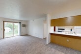 Located at 140 Lauff Drive in Milan, Michigan, this 2-bedroom, 1-bathroom residence offers a practical and well-organized single-floor layout. The open living and dining area is carpeted throughout and features a sliding glass door that leads to a private balcony with outdoor views, filling the space with natural light. A wall-mounted air conditioning unit serves the main living area. The kitchen connects to the living and dining space via a pass-through counter with a built-in sink and warm wood-toned cabinetry above, creating an open and interactive feel. It is equipped with a range and refrigerator. The primary bedroom is generously sized, featuring two double sliding closets with wood-panel doors and plush carpeting. The second bedroom includes a large window with natural light, baseboard heating, and access to an additional closet. A spacious walk-in closet with wire shelving provides extra storage. The full bathroom includes tile flooring, a wide vanity with under-cabinet storage, a large mirror, and baseboard heating. A hallway connects all rooms efficiently. With four closets total throughout the residence, storage is a notable highlight of this well-appointed home.