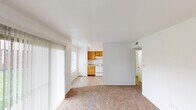 Located at 2518 Tamarack Ln in Indianapolis, Indiana, this single-floor residence offers a practical and comfortable layout designed for everyday living. The open living area is finished with wall-to-wall carpet and features large sliding glass doors dressed with vertical blinds, allowing generous natural light to pour in while providing direct access to the outdoors. An additional window in the living space further brightens the interior. The kitchen flows naturally from the living area and is outfitted with warm honey-toned wood cabinetry offering ample storage, light-colored countertops, a double stainless steel sink, a white electric range with a range hood, and a refrigerator, all set on easy-care tile flooring. The bedrooms are carpeted and bathed in natural light through windows that overlook the surrounding neighborhood, providing a clean and restful atmosphere. The bathroom includes a full tub and shower combination with white surround walls and built-in corner shelving, complemented by chrome fixtures. Throughout the home, crisp white walls and clean lines create a bright, neutral backdrop that is easy to personalize. The single-story layout ensures seamless, step-free movement throughout the entire residence.