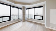 Located on the 22nd floor of 517 Richmond Street in downtown London, Ontario, this modern 2-bedroom, 2-bathroom unit offers a well-designed open-concept layout with contemporary finishes throughout. Light-toned hardwood flooring flows seamlessly across the entire space, complemented by soft grey walls and crisp white trim.

The kitchen is a standout feature, boasting sleek white cabinetry, a marble-style tile backsplash, stainless steel appliances, and a large central island with quartz countertops and stylish pendant lighting. A floor-to-ceiling sliding glass door opens to a private balcony, flooding the kitchen and adjoining dining and living area with natural light and sweeping city views.

The primary bedroom is generously sized, featuring expansive floor-to-ceiling windows on two walls, a curved concrete column accent, and panoramic views of the London skyline. The second bedroom also benefits from large windows with balcony access and city views. Both bathrooms are finished with marble-look tile, floating vanities, and round black-framed mirrors.

Additional highlights include a dedicated laundry room, a hallway closet, and a welcoming entry hallway with double grey doors and recessed lighting, completing this polished high-rise residence.