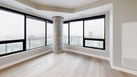 Located on the 22nd floor of 517 Richmond Street in downtown London, Ontario, this modern 2-bedroom, 2-bathroom unit offers a well-designed open-concept layout with contemporary finishes throughout. Light-toned hardwood flooring flows seamlessly across the entire space, complemented by soft grey walls and crisp white trim.

The kitchen is a standout feature, boasting sleek white cabinetry, a marble-style tile backsplash, stainless steel appliances, and a large central island with quartz countertops and stylish pendant lighting. A floor-to-ceiling sliding glass door opens to a private balcony, flooding the kitchen and adjoining dining and living area with natural light and sweeping city views.

The primary bedroom is generously sized, featuring expansive floor-to-ceiling windows on two walls, a curved concrete column accent, and panoramic views of the London skyline. The second bedroom also benefits from large windows with balcony access and city views. Both bathrooms are finished with marble-look tile, floating vanities, and round black-framed mirrors.

Additional highlights include a dedicated laundry room, a hallway closet, and a welcoming entry hallway with double grey doors and recessed lighting, completing this polished high-rise residence.