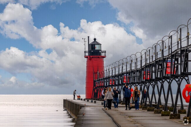 Residents walk along a boardwalk near a lighthouse.