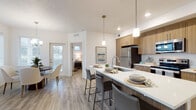 Located at 12000 West Fairview Avenue in Boise, Idaho, this single-story unit offers a well-designed, contemporary layout with thoughtful finishes throughout. The entryway is defined by a striking sliding barn door that opens into the main living corridor, where light wood-look flooring extends seamlessly through the primary living areas.

The open-concept kitchen is a central highlight, featuring warm wood cabinetry, stainless steel appliances, and a large island with a white quartz countertop that comfortably accommodates bar seating for several guests. Pendant lighting adds a refined touch above the island, while recessed lighting provides consistent illumination throughout. The adjoining dining area benefits from multiple windows, a chandelier overhead, and direct access to an exterior door, filling the space with natural light.

Two bedrooms offer comfortable, carpeted retreats. One bedroom features windows on multiple walls for added brightness, while the other connects to a hallway with closet access. The bathroom is appointed with wood-toned cabinetry, white quartz countertops, wood-look tile flooring, and a full tub-shower combination. A dedicated in-unit laundry area with a full-size washer and dryer adds everyday convenience. An additional flex room provides versatile space suitable for a home office or sitting room.