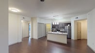 This well-appointed 3-bedroom, 2-bathroom single-story residence offers a thoughtfully designed open-concept layout that seamlessly connects the living area and kitchen. Rich, dark hardwood-style flooring extends throughout the main living spaces, creating a warm and cohesive aesthetic. The kitchen is a standout feature, equipped with stainless steel appliances including a refrigerator, range, and microwave, complemented by dark espresso cabinetry, granite countertops, and a center island with a double sink. A dedicated walk-in pantry provides generous storage. The living area is bright and airy, featuring a ceiling fan and a window with blinds that allows natural light to fill the room. Each of the three bedrooms is carpeted for comfort and includes a ceiling fan and window with blinds. The primary bathroom offers a vanity with granite countertops, dark cabinetry, a tub-shower combination, and direct access to a walk-in closet. The second bathroom mirrors the same refined finishes, including granite countertops and a shower. Ample closet space is found throughout the residence, including multiple double-door closets visible from the main living area.