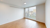 Located at 909 N 39th St in Seattle's vibrant Fremont neighborhood, this modern studio offers a thoughtfully designed single-floor layout that maximizes every square foot. The open-plan living, dining, and kitchen area forms the heart of the space, bathed in natural light from large floor-to-ceiling windows that frame views of the surrounding Seattle streetscape. Clean white walls and warm hardwood-style flooring run throughout, creating a bright, cohesive aesthetic. The kitchen is equipped with stainless steel appliances, including an electric range, and features natural wood cabinetry that adds a touch of warmth to the minimalist design. The full bathroom continues the clean, modern palette with white finishes, a full tub-shower combination, a vanity with an integrated sink, and a large mirror. A standout convenience feature is the dedicated in-unit laundry closet, which houses a full stacked washer and dryer—a practical amenity that sets this space apart. An electrical panel is also neatly integrated into the hallway wall. The overall ambiance is clean, contemporary, and efficient, making excellent use of its compact footprint in one of Seattle's most walkable and dynamic neighborhoods.