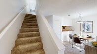 This two-story home offers a well-organized layout thoughtfully divided between two floors. The main level features a living room with carpet flooring, a ceiling fan, and a fireplace that serves as a focal point of the space. Adjacent to the living area is a kitchen with warm wood cabinetry, stone-look countertops, and hardwood flooring, providing a practical and inviting space for cooking. A carpeted staircase with a white banister connects both floors seamlessly.

The upper level houses the two bedrooms, each carpeted and designed for comfortable living. The primary bedroom offers a generous footprint, while the second bedroom connects directly to one of the three bathrooms — a convenient layout for everyday use. The bathrooms are well-appointed, featuring stone-look countertops, single vanity sinks, and shower-tub combinations. A hallway and two closets on the upper floor add to the home's practical storage options.

Throughout the home, textured ceilings and neutral wall tones create a cohesive, understated aesthetic. The mix of carpet and hardwood flooring across different areas adds variety and warmth. Overall, this home delivers a compact yet fully equipped living experience across its two levels.