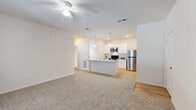 Located at 2151 W Moore St in Sherman, TX, this one-bedroom, one-bathroom unit offers a thoughtfully designed single-floor layout that maximizes functionality. The open-concept kitchen and living area serves as the heart of the home, where warm-toned carpet in the living space transitions to light wood-style flooring in the kitchen. The kitchen is well-equipped with white shaker cabinetry, granite countertops, a peninsula with a built-in sink and pendant lighting overhead, and a full suite of stainless steel appliances including a refrigerator, range, and microwave. A pantry provides additional storage. The living area is bright and open, featuring a ceiling fan and a glass door that introduces natural light. The bedroom offers a comfortable footprint with plush carpet, a ceiling fan, a window with blinds, and access to two closets. The full bathroom includes a granite-topped vanity with white cabinetry, wood-style flooring, and a full soaking tub with a shower. Additional conveniences include a dedicated laundry room, a utility room, and a hallway connecting the private spaces. The unit's clean, neutral palette and modern finishes create a cohesive and practical living environment.