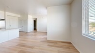 Located on the third floor at 3644 Harrison St in Riverside, California, this well-appointed one-bedroom, one-bathroom unit offers a clean, modern design with a thoughtful layout across a single floor. Light wood-tone flooring runs throughout the entire unit, creating a cohesive and airy aesthetic that complements the crisp white walls and neutral color palette.

The open-concept kitchen and living area serves as the heart of the unit. The kitchen is outfitted with white shaker-style cabinetry, a light quartz countertop, and a full suite of stainless steel appliances including a French door refrigerator, electric range, over-the-range microwave, and dishwasher. A peninsula island provides additional counter space and separates the kitchen from the living area, making the space ideal for both cooking and entertaining.

The bedroom is a comfortably sized, light-filled room featuring a window with views of the surrounding neighborhood's mature trees, a closet with louvered doors, and a clean, minimalist finish. The bathroom includes a white vanity with a gray quartz countertop, a framed mirror, and a shower-tub combination with open shelving. A hallway connects the main living spaces, offering convenient flow throughout the unit.