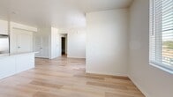 Located on the third floor at 3644 Harrison St in Riverside, California, this well-appointed one-bedroom, one-bathroom unit offers a clean, modern design with a thoughtful layout across a single floor. Light wood-tone flooring runs throughout the entire unit, creating a cohesive and airy aesthetic that complements the crisp white walls and neutral color palette.

The open-concept kitchen and living area serves as the heart of the unit. The kitchen is outfitted with white shaker-style cabinetry, a light quartz countertop, and a full suite of stainless steel appliances including a French door refrigerator, electric range, over-the-range microwave, and dishwasher. A peninsula island provides additional counter space and separates the kitchen from the living area, making the space ideal for both cooking and entertaining.

The bedroom is a comfortably sized, light-filled room featuring a window with views of the surrounding neighborhood's mature trees, a closet with louvered doors, and a clean, minimalist finish. The bathroom includes a white vanity with a gray quartz countertop, a framed mirror, and a shower-tub combination with open shelving. A hallway connects the main living spaces, offering convenient flow throughout the unit.