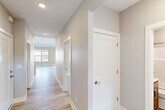 Located at 1580 Woodland Way in Okemos, Michigan, this well-appointed two-story home offers four bedrooms and five bathrooms across two generously sized floors. The main level features an open-concept layout where the kitchen, dining, and living areas flow seamlessly together. The kitchen is a standout, showcasing a large center island with a sink, quartz countertops, two-tone cabinetry, stainless steel appliances, a statement range hood, and stylish pendant lighting above vaulted ceilings. The adjacent family room is bathed in natural light from large windows and a sliding glass door that opens to a deck with neighborhood views, complemented by a fireplace with a classic white mantel. Light hardwood flooring runs throughout the main living areas, lending warmth and continuity. A dedicated laundry room on the upper level is outfitted with full-size washer and dryer units, ample white cabinetry, and a built-in folding counter. The bedrooms are carpeted and include generous closet space. Five well-appointed bathrooms serve the household with clean, modern finishes. The attached garage provides convenient parking and storage, while the unfinished basement offers significant potential for future expansion or additional storage.