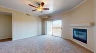 This single-floor residence offers a thoughtfully arranged layout with a comfortable mix of functional spaces. The living room serves as the central gathering area, finished with plush wall-to-wall carpeting, crown molding, and a ceiling fan with a light fixture. A corner fireplace with a clean surround adds a focal point to the room, while a sliding glass door opens onto a private balcony, allowing natural light to fill the space and offering views of the surrounding outdoors.

The kitchen is well-equipped, featuring rich dark wood cabinetry with sleek hardware, granite-style countertops, wood-look flooring, and a full suite of stainless steel appliances including a range, microwave, refrigerator, and dishwasher. Ample counter and cabinet space supports practical everyday use.

The bedrooms are carpeted and include large windows fitted with vertical blinds that provide natural light and outdoor views. Ceiling fans are present for comfort. Closet space is available, with built-in shelving offering organized storage.

The bathrooms feature dark wood vanities with granite-style countertops, white tile tub-shower combinations, and wood-look flooring, maintaining a consistent and cohesive design throughout the residence.