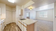 This two-bedroom, one-bathroom unit in Aurora, Colorado offers a practical and well-organized single-floor layout. The kitchen is a standout feature, designed as a galley-style space with white cabinetry accented by light wood trim, a double-basin sink, an electric range, a refrigerator, a dishwasher, and a peninsula counter that opens toward the living area. The flooring in the kitchen and main hallway is hardwood-style, adding a clean, durable finish to the high-traffic areas. The living area flows naturally from the kitchen, featuring neutral carpet and a window that brings in natural light. Both bedrooms are carpeted, with neutral wall tones and windows fitted with blinds. The primary bedroom is generously sized and includes access to a spacious walk-in closet with double hanging rods and shelving for ample storage. A second closet is also available within the unit. The full bathroom is finished with hardwood-style flooring, a single vanity with under-sink cabinetry, a large mirror with overhead lighting, and a tub-shower combination. The textured ceilings and consistent neutral palette throughout give the space a cohesive and functional character, well-suited for everyday living.