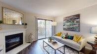 This single-story residence offers a well-organized layout that connects living, dining, and kitchen areas in an open, cohesive flow. The living room serves as the focal point of the home, highlighted by a white brick fireplace with a classic mantel, dark hardwood-style flooring, and a sliding glass door that opens to a private balcony, allowing natural light to fill the space. A dedicated dining area sits adjacent to the living room, providing a seamless transition between spaces.

The kitchen features white shaker-style cabinetry, dark countertops, a stainless steel dishwasher, and a undermount sink. A skylight overhead enhances brightness, while a window with plantation shutters adds ventilation and additional natural light.

The bedroom is generously proportioned, finished with plush wall-to-wall carpeting and a large window that frames outdoor greenery. The room connects conveniently to the rest of the unit, with the full bathroom nearby. The bathroom includes a tub-shower combination and durable hardwood-style flooring in a clean, neutral palette.

A dedicated in-unit laundry area houses a full-size top-loading washer and dryer with overhead shelving for storage, adding everyday practicality to this comfortable, well-appointed residence.