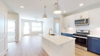 Located at 3930 Peachtree Rd in Brookhaven, Georgia, this thoughtfully designed single-floor residence combines modern aesthetics with functional living. The open-concept layout seamlessly connects the kitchen and living area, creating an inviting, airy atmosphere filled with natural light from large windows fitted with blinds.

The kitchen is a standout feature, showcasing a striking two-tone cabinet design with crisp white upper cabinetry and bold navy blue lower cabinets, accented by gold hardware. A generous center island with a white quartz countertop and a gold-finish faucet serves as the focal point, illuminated by elegant pendant lighting. Stainless steel appliances, including a gas range, microwave, and French door refrigerator, complete the space, all set atop light-toned hardwood flooring.

The living area extends naturally from the kitchen, featuring a ceiling fan and a glass-panel door that brings in additional natural light. Bedrooms are carpeted for comfort, each equipped with ceiling fans and windows offering outside views. One bedroom features hardwood flooring, providing a versatile space.

The bathrooms are finished with clean white tile, including a tub-shower combination and a glass-enclosed shower. A walk-in closet with wire shelving provides ample storage. Throughout, the residence maintains a bright, neutral palette that enhances its modern, welcoming character.