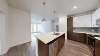 Located at 400 North Rome Avenue in Tampa's desirable Hyde Park neighborhood, this well-appointed single-floor residence offers three bedrooms, two bathrooms, and a thoughtfully designed layout. The open-concept kitchen serves as the heart of the home, showcasing a large central island with a quartz countertop, undermount sink, and pendant lighting. Two-tone cabinetry — combining rich dark wood lower cabinets with crisp white uppers — pairs elegantly with a soft blue tile backsplash and a full suite of stainless steel appliances. The living area flows naturally from the kitchen, featuring wood-look plank flooring, a ceiling fan, and glass French doors that invite natural light and provide outdoor access. Each bedroom is finished with the same durable wood-look flooring, neutral walls, and ceiling fans or lighting fixtures. The primary bedroom is served by a spacious walk-in closet outfitted with wire shelving systems for organized storage. The two bathrooms maintain the home's modern aesthetic, one featuring a glass-enclosed walk-in shower and the other a full soaking tub with sliding glass doors, both with dark wood vanities and clean white quartz countertops throughout.