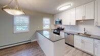 This renovated two-bedroom, one-bathroom residence at Troy Hills Edgebrook in Parsippany, NJ offers a thoughtfully updated single-floor layout. Wood-style flooring runs throughout the unit, providing a cohesive and contemporary aesthetic. The soft sage-green wall tones complement the clean white trim and baseboards found in every room.

The kitchen serves as a functional centerpiece, featuring white shaker-style cabinetry, granite countertops, a peninsula with additional prep space, and a full suite of stainless steel appliances including a gas range, microwave, dishwasher, and refrigerator. Two windows allow natural light to fill the space. The living area includes a sliding glass door with vertical blinds, providing outdoor views and additional natural light.

Both bedrooms are well-proportioned with wood-style flooring, soft neutral walls, and ample wall outlets. One bedroom includes a ceiling fan with a light fixture and windows overlooking the surrounding area. The bathroom features a tub-shower combination with glass sliding doors, white subway tile accented by a decorative mosaic border, a white vanity, and a frosted window for natural light and privacy.