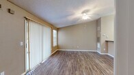 Located at 5009 Park Central Dr in Orlando, FL, this single-floor, one-bedroom, one-bathroom residence offers a functional and comfortable layout. The living room is bright and welcoming, featuring durable wood-style flooring, warm neutral-toned walls, a textured ceiling, and a ceiling fan with light fixture. A sliding glass door fitted with vertical blinds allows natural light to fill the space and provides access to the outdoors. The kitchen is efficiently designed with white cabinetry, dark granite-style countertops, a stainless steel double sink, and black appliances including a refrigerator and electric range. Wood-style flooring continues throughout the kitchen, which connects seamlessly to the main living area. The bedroom is a comfortable size, finished with plush carpeting, a ceiling fan, a window with blinds for natural light, and direct access to a walk-in closet outfitted with wire shelving. The bathroom features a white vanity with dark countertops, a large mirror with overhead lighting, and consistent wood-style flooring. The walk-in closet offers carpeted flooring and ample shelving. Throughout the residence, warm beige tones and clean white trim create a cohesive and inviting atmosphere.