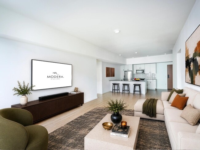 Open living area with clean-lined finishes, a generous lounge space, and a kitchen with bar seating designed for gathering and everyday comfort. - Modera Bridle Trails